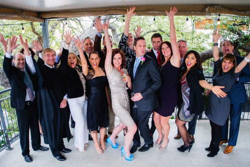 Wedding party cheering with the bride and groom on a covered patio