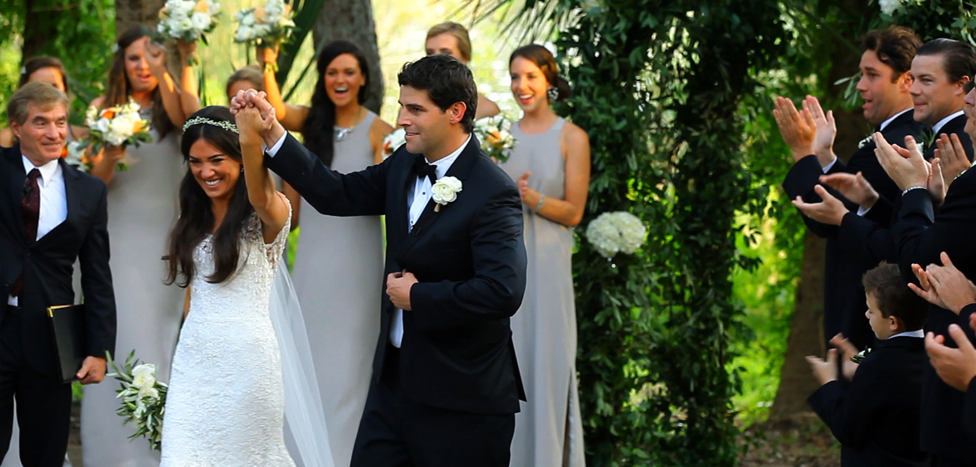 Bride and groom celebrating their recessional as the wedding party cheers